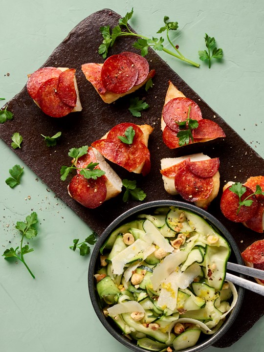 Kyllingebryst stegt med skiver af chorizopølse, serveret med courgettesalat med parmesan og hasselnødder